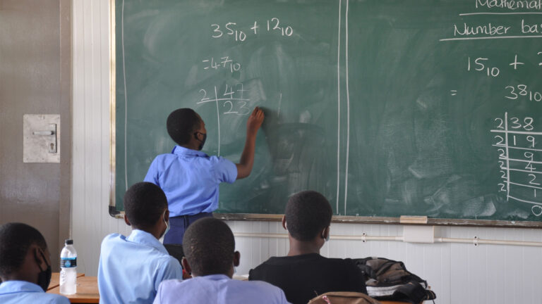 Little boy solving math problem on the chalkboard in classroom