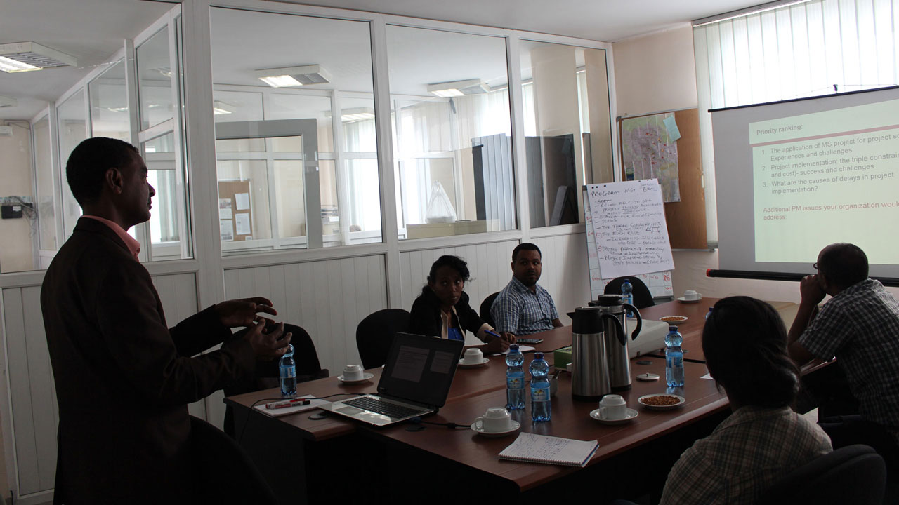 Training workshop led by male presenter with four participants seated around a table