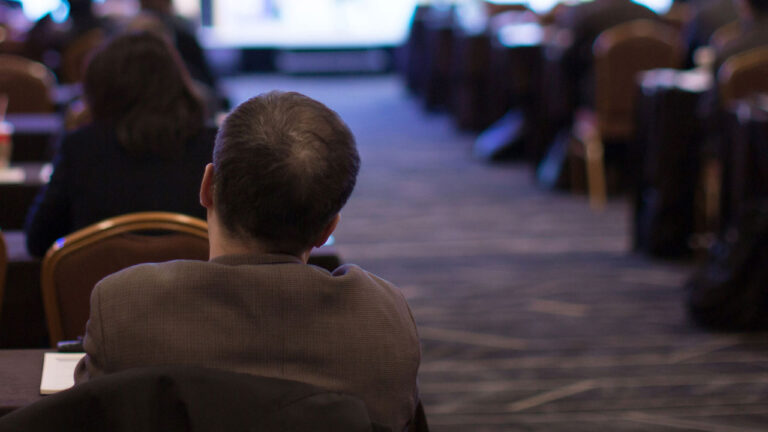 People sitting in rows of chairs at a conference