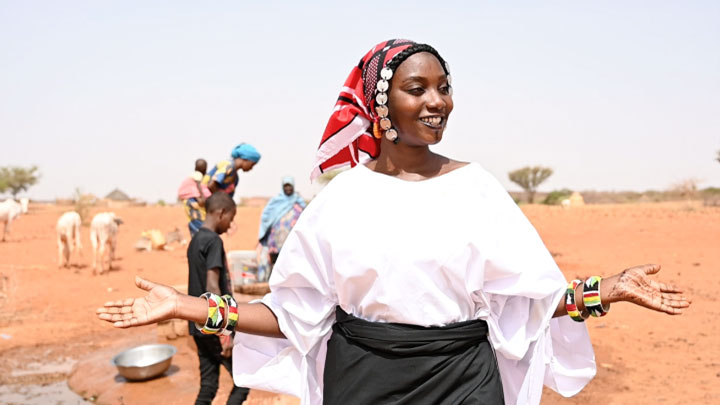 Woman wearing traditional outfit and smiling with hands open