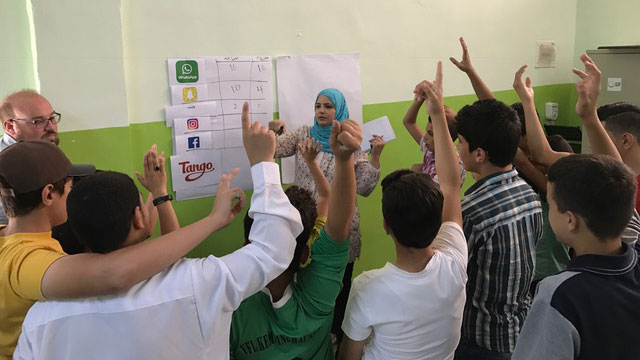 A group of students in a classroom with their hands up